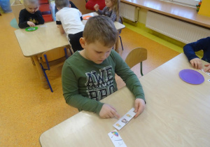Chłopiec rozwiązuje rebusy fonetyczny.